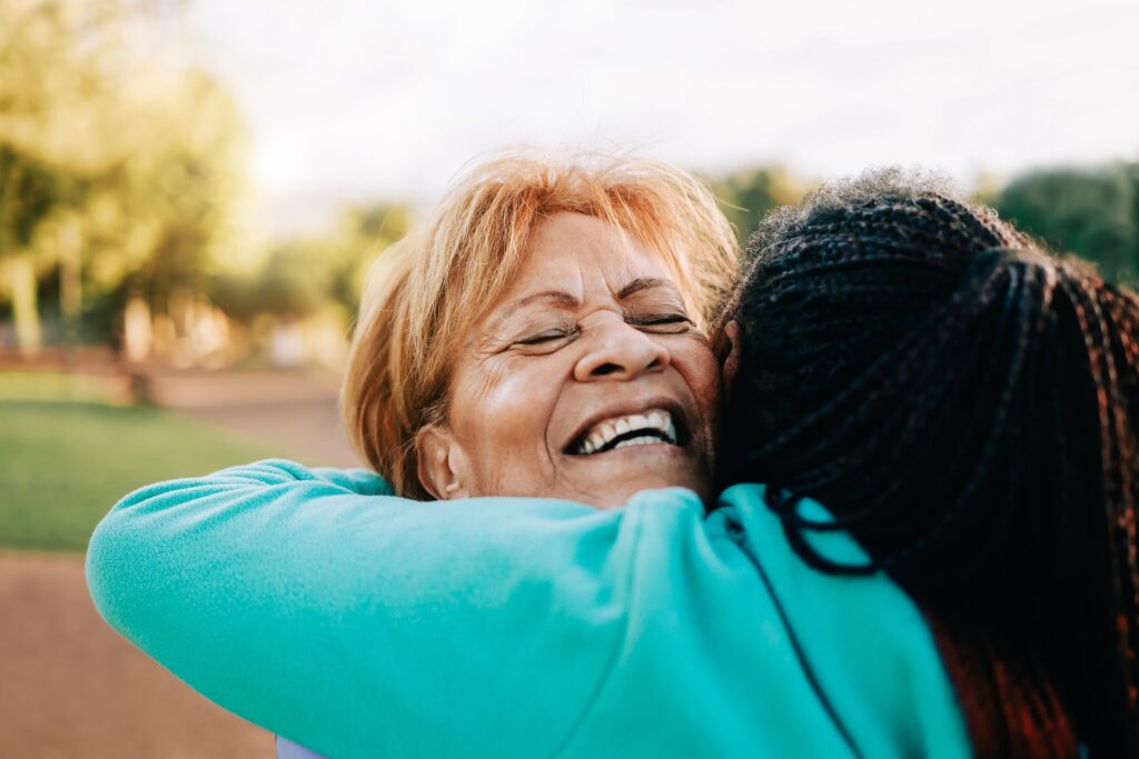 Multiracial senior women hugging each other at city park